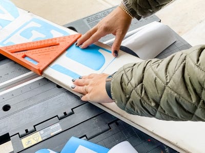 using the measuring tool and placing the stencil letters on to the wood piece