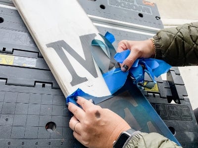 peeling off the stencils from wood piece