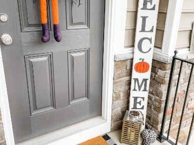 welcome sign with pumpkin as O next to door on front porch