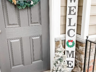 welcome sign with wreath as O next to door on front porch