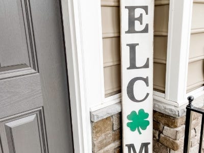 welcome sign with four leaf clover as O next to door on front porch