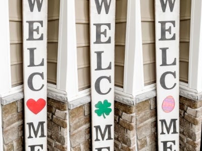 welcome sign with heart, four leaf clover and egg as O next to door on front porch side by side