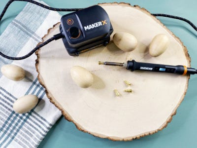 Blank wood egs next to rotary tool on top of wood plate