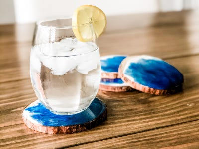 Water glass sitting on top of resin coaster in front of 3 coasters stacked