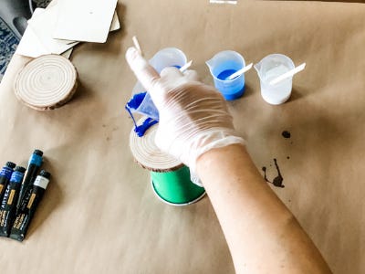 Hand pouring the darkest blue color on to wood coaster