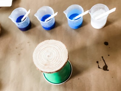 Wood coaster sitting on top of cup in front of 4 blue mixed cups