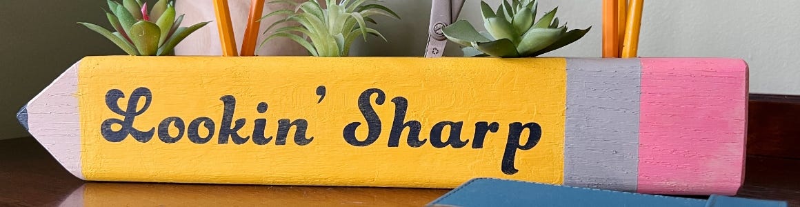 wooden block painted like a pencil with looking sharp cursive writing