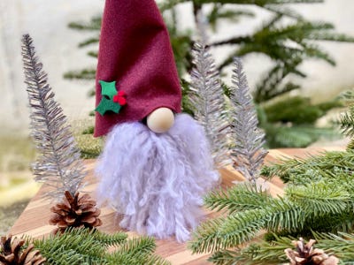 yarn and felt face gnome between Christmas trees