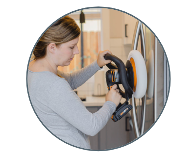 a woman using the buffer on a stainless steel refridgerator