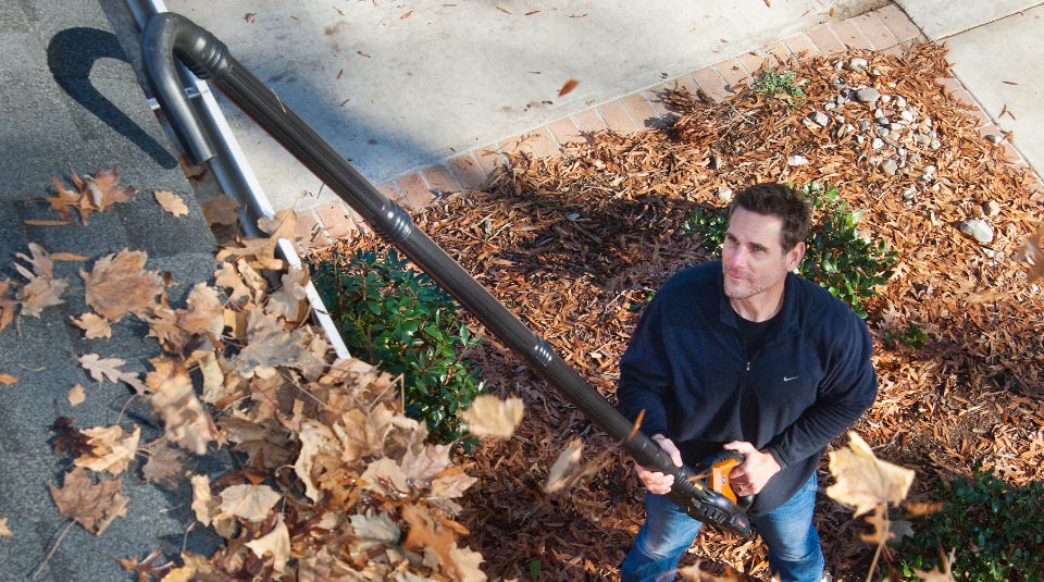 man using assembled gutter cleaning kit to clean the leaves out of a gutter