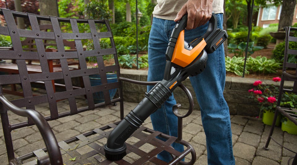 man using the blower to clean off a lawn chair