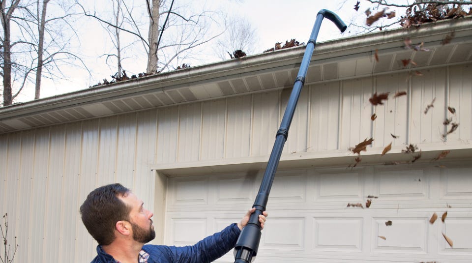 man using the gutter kit assembled and clearing out his gutters