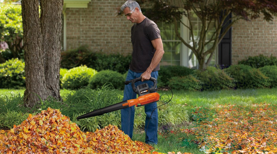 man holding the blower, mulcher, vac in a pile of leaves