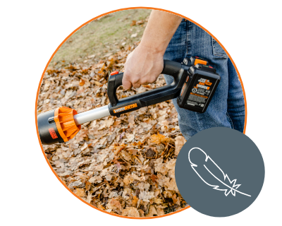 person holding the blower in their left hand standing in the yard filled with dry leaves