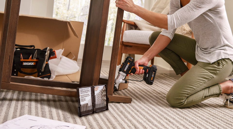 woman using a worx drill on a bed frame with the drill bet set on the left