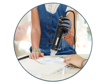 image of a woman using the heat gun on a stencil