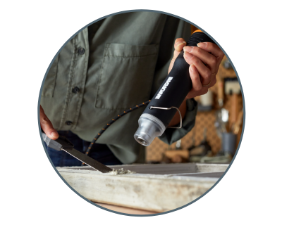 image of a man using the heat gun to melt and scrape putty from a piece of wood