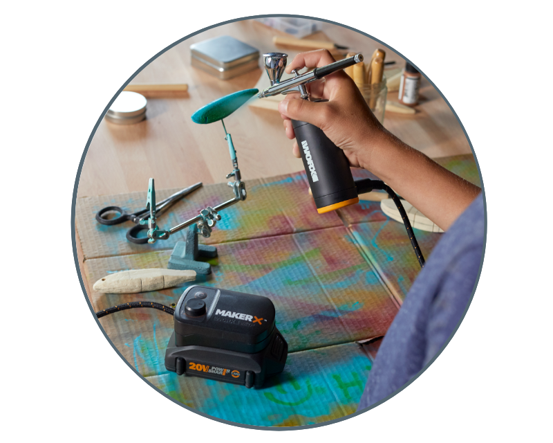 image of a woman using the air brush to paint a wooden handle