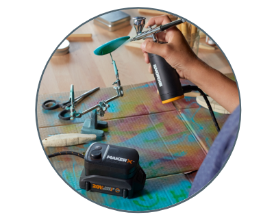 image of a woman using the air brush to paint pieces of wood