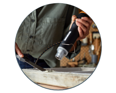 person using the heat gun on a piece of wood