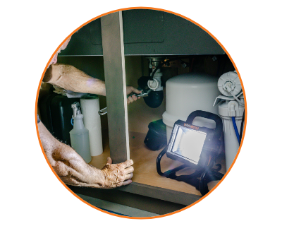 person using the work light to do work under a sink