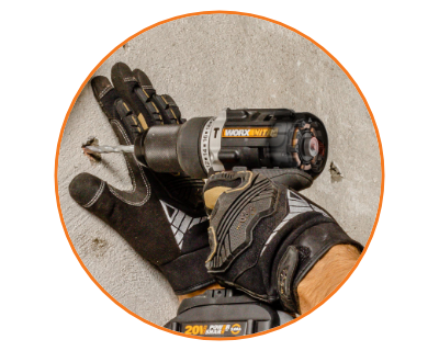 person wearing gloves using the drill to drill holes in dry wall