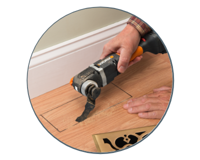 close up image of a man using the sonicrafter to cut pieces from a wood floor