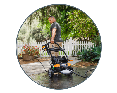 person pulling the pressure washer down a driveway