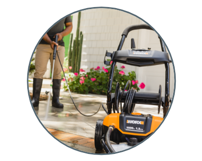 person wearing rubber boots and cleaning their sidewalk with the pressure washer in the foreground