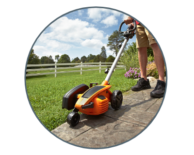 image of a person using the edger to trim the grass next to the sidewalk